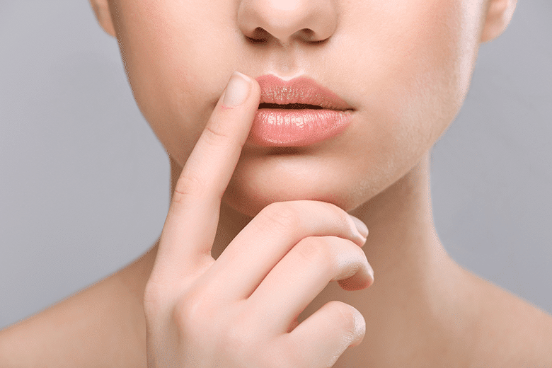 Young female covering lip due to mouth sores. These sores are painful, and they take longer to heal than we wish, but they only show up occasionally. 