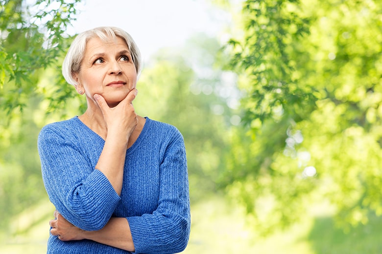 Older woman pondering questions while taking a walk in the park