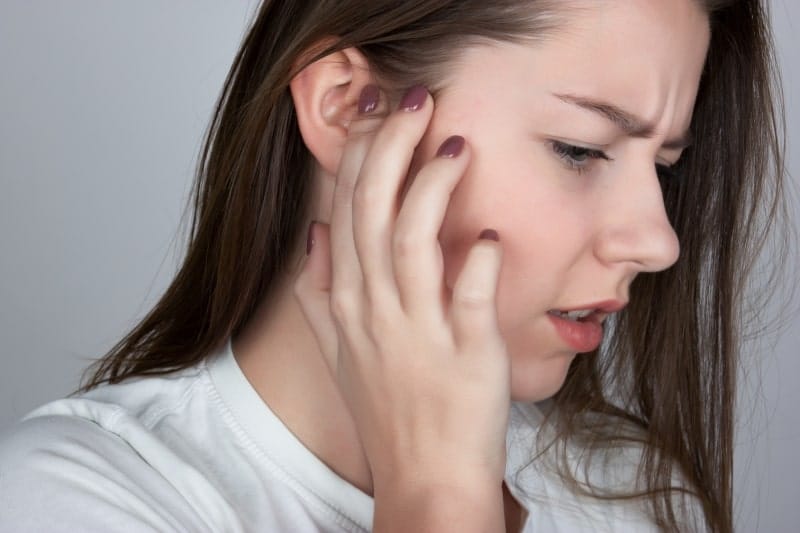 woman with an itchy ear, suffering from TMJ