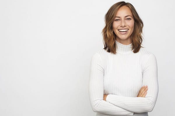 attractive woman crosses her arms and laughs with a full smile