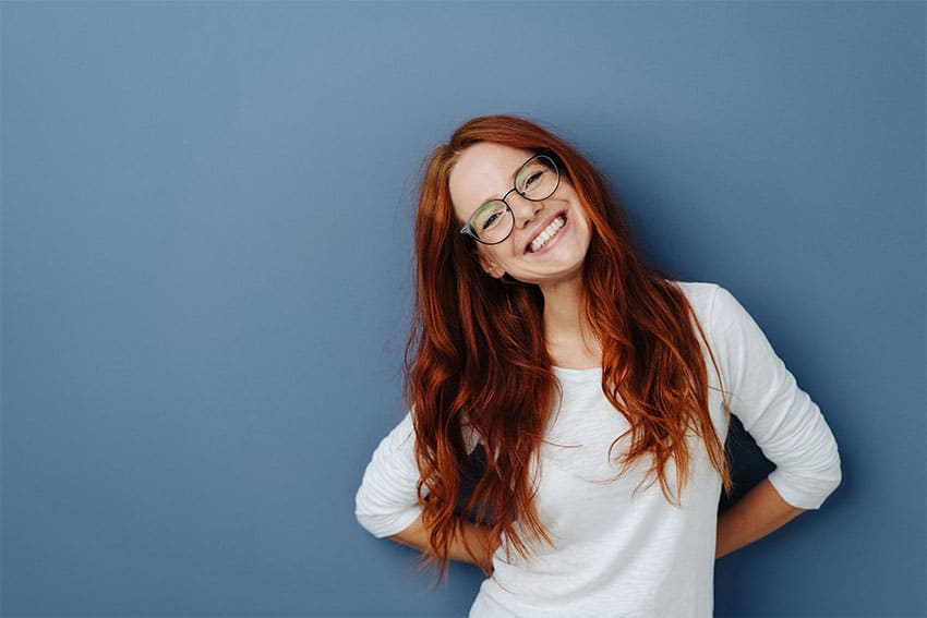 Cute red haired woman tilts her head and shows off her amazing smile